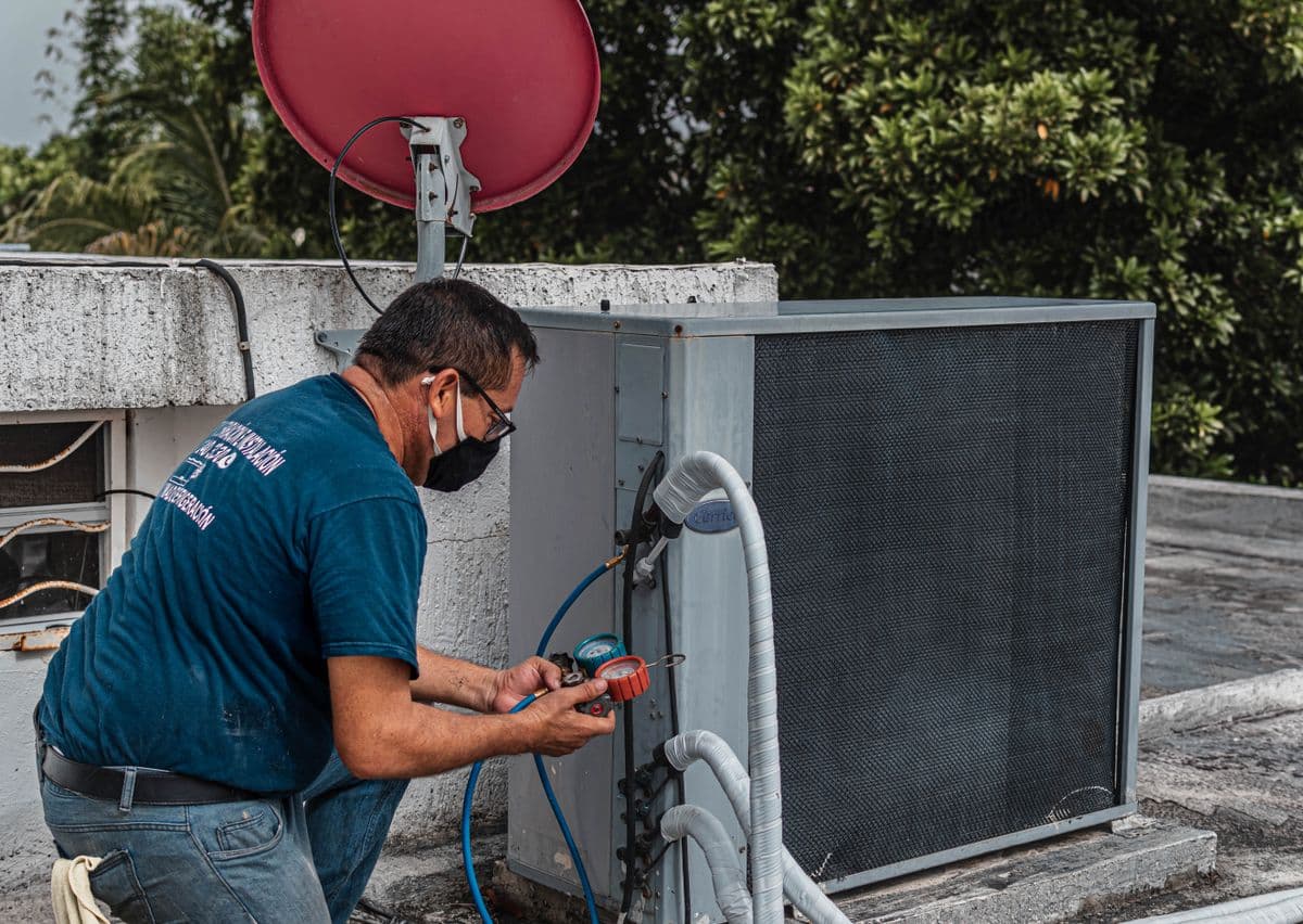 Technician repairing an air conditioner outdoor unit at a home in Chennai
